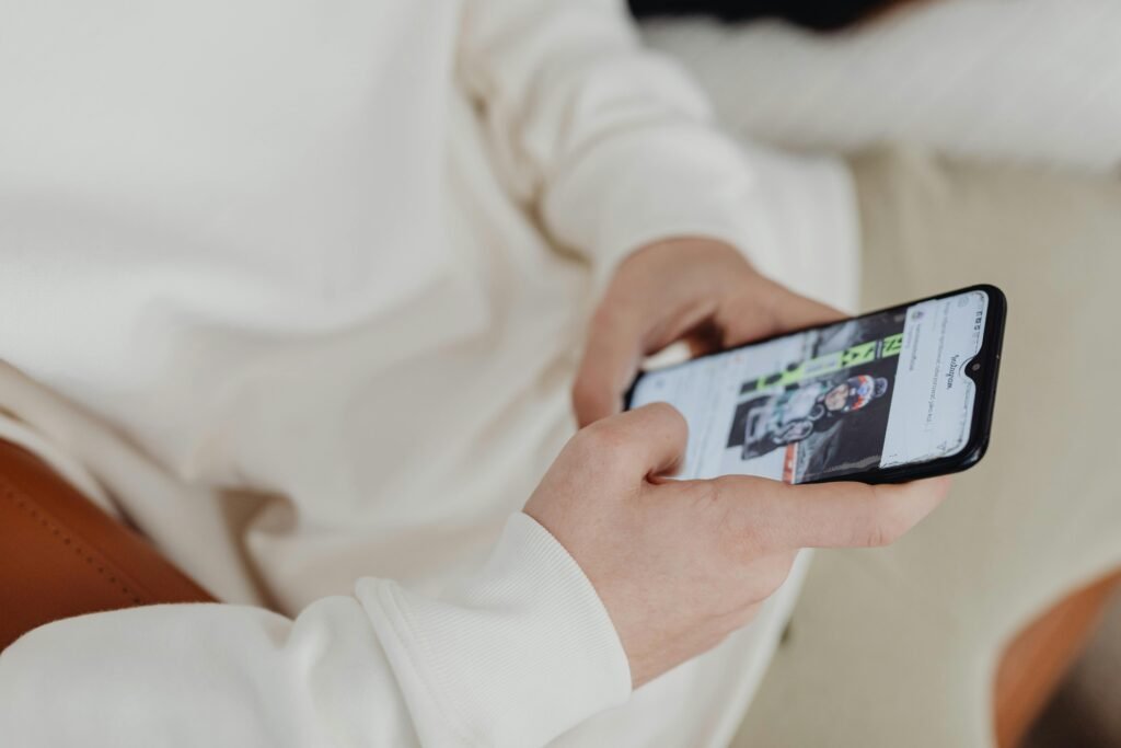pexels-photo-6255899-6255899 A close-up view of hands holding a smartphone displaying a sports image indoors.